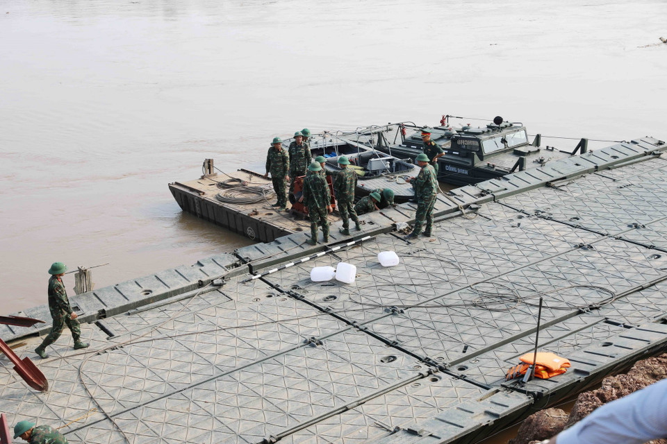 Các lực lượng chức năng hạ thủy một số nhịp dùng để lắp cầu phao trên sông Hồng, cách cầu Phong Châu bị sập khoảng 400m về phía hạ lưu. (Ảnh: Tạ Toàn/TTXVN)