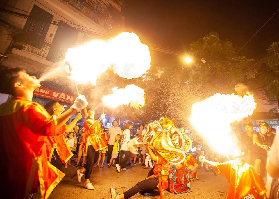 Tiết mục múa lân với lửa tạo nên không khí sôi động trên phố Hàng Chiếu. (Ảnh: Minh Công/TTXVN)