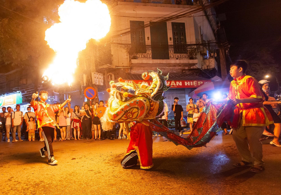 Tiết mục múa lân với lửa tạo nên không khí sôi động trên phố Hàng Chiếu. (Ảnh: Minh Công/TTXVN)