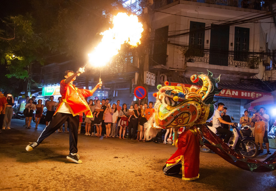 Tiết mục múa lân với lửa tạo nên không khí sôi động trên phố Hàng Chiếu. (Ảnh: Minh Công/TTXVN)