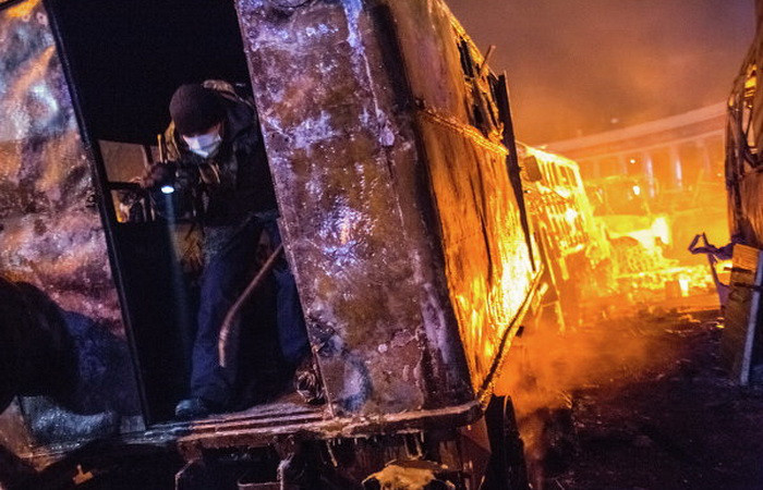 Xe đặc chủng của cảnh sát bị thiêu rụi còn trơ lại khung sắt, nhưng đã được người biểu tình tận dụng làm nơi ẩn nấp.