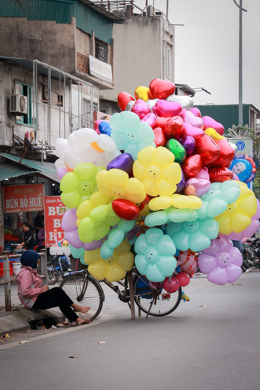 Tiểu thương kinh doanh bóng bay ế ẩm ngồi chờ khách. (Ảnh: Minh Hiếu/Vietnam+)