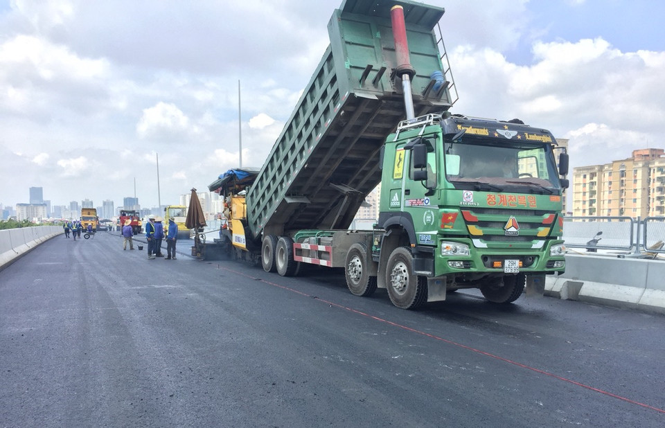 Nhà thầu đang tập trung nhân lực và nguyên liệu để thảm nhựa mặt đường. (Ảnh: Việt Hùng/Vietnam+)