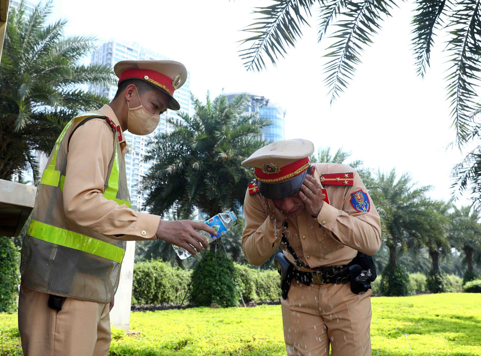 Các chiến sỹ Cảnh sát giao thông số 6 tranh thủ vài phút nghỉ ngơi để rửa mặt, làm dịu cơn nóng. (Ảnh: Phạm Kiên/TTXVN)