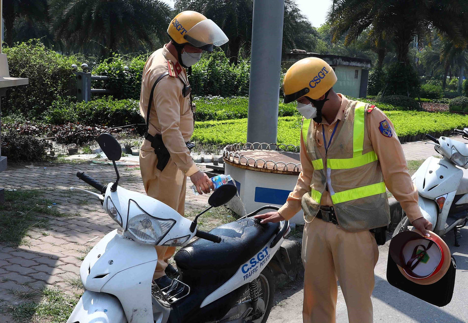 Sau mỗi ca trực, các chiến sỹ Cảnh sát Giao thông phải đổ nước làm mát yên xe do để lâu dưới nền trời nhiệt độ cao. (Ảnh: Phạm Kiên/TTXVN)