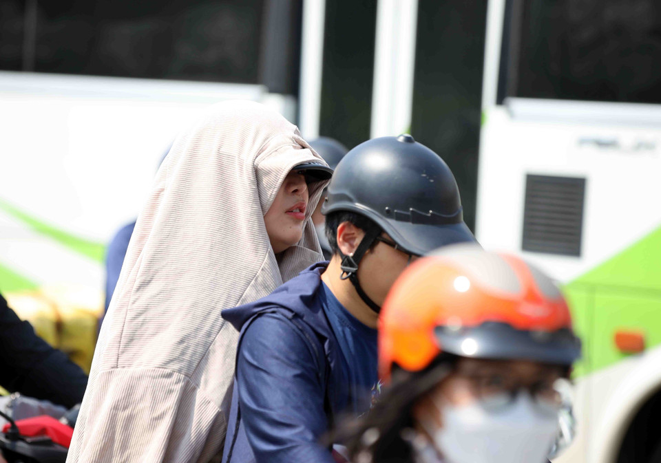 Người dân thủ đô che chắn kín mít khi ra đường trong thời điểm nắng gắt. (Ảnh: Phạm Kiên/TTXVN)