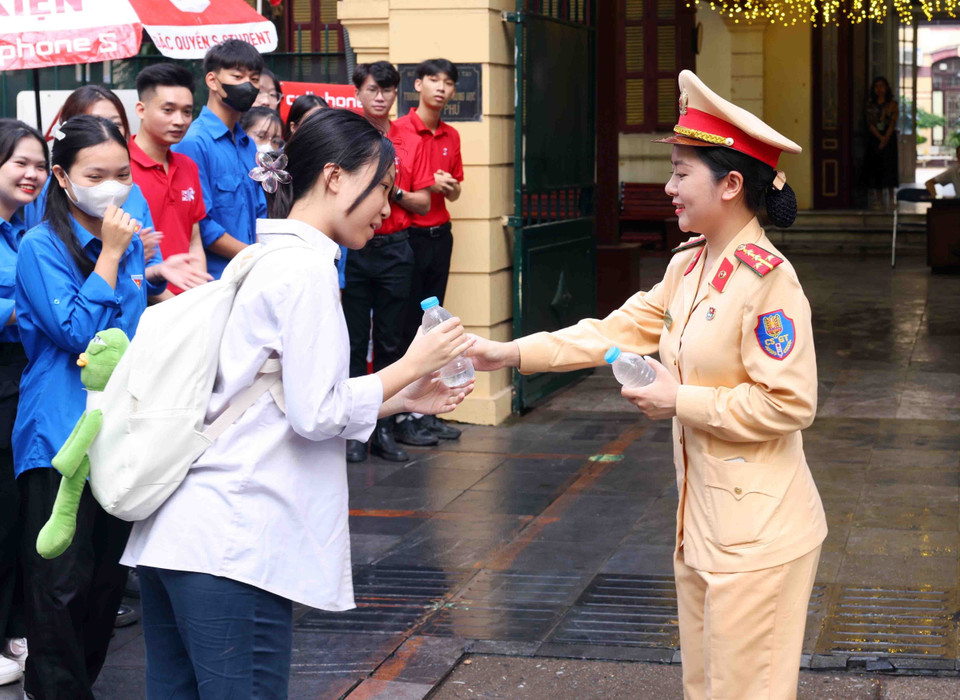 Cán bộ, chiến sỹ phòng Cảnh sát Giao thông, Công an thành phố Hà Nội phát nước, động viên các sỹ tử trước giờ thi. (Ảnh: Phạm Kiên/TTXVN)