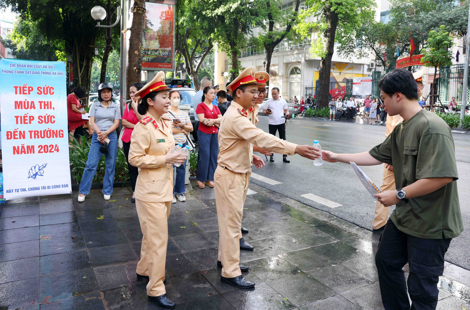 Cán bộ, chiến sỹ phòng Cảnh sát Giao thông, Công an thành phố Hà Nội phát nước, động viên các sỹ tử tại điểm thi trường THPT Trần Phú-Hoàn Kiếm. (Ảnh: Phạm Kiên/ TTXVN)