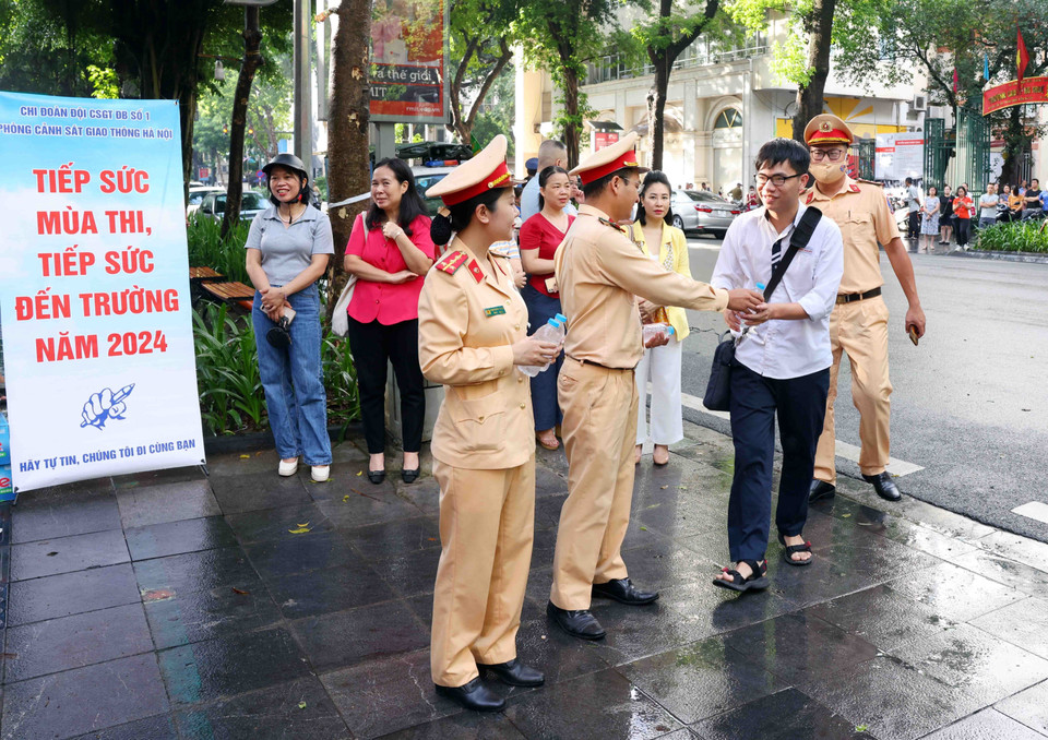 Cán bộ, chiến sỹ phòng Cảnh sát Giao thông, Công an thành phố Hà Nội phát nước, động viên các sỹ tử tại điểm thi trường THPT Trần Phú-Hoàn Kiếm. (Ảnh: Phạm Kiên/ TTXVN)