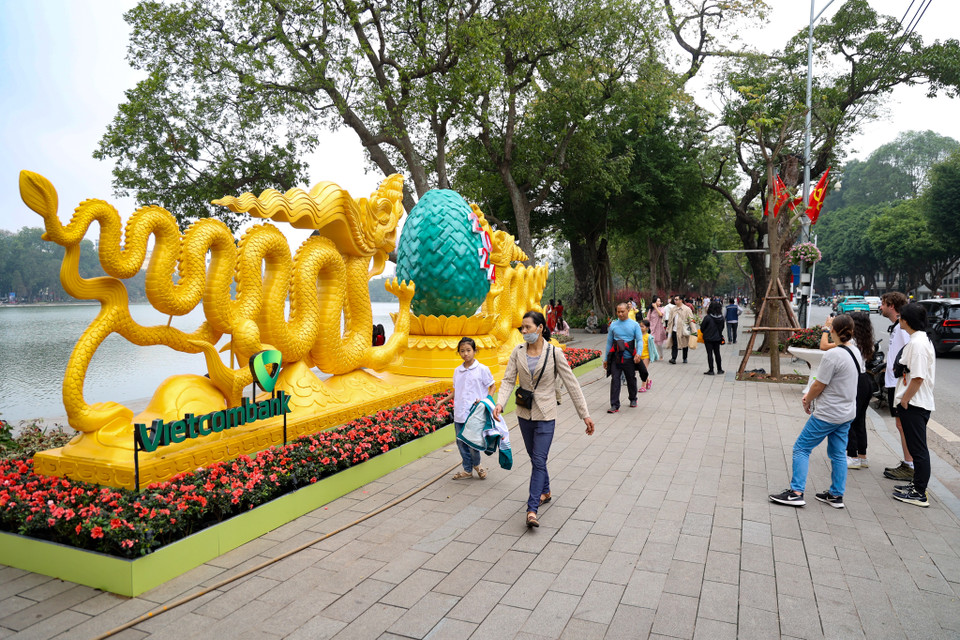 Nhiều người tranh thủ thời gian chọn cách đi dạo quanh Hồ Hoàn Kiếm để hòa nhịp vào không khí rộn ràng dịp cận Tết của Thủ đô. (Ảnh: Minh Hiếu/Vietnam+)