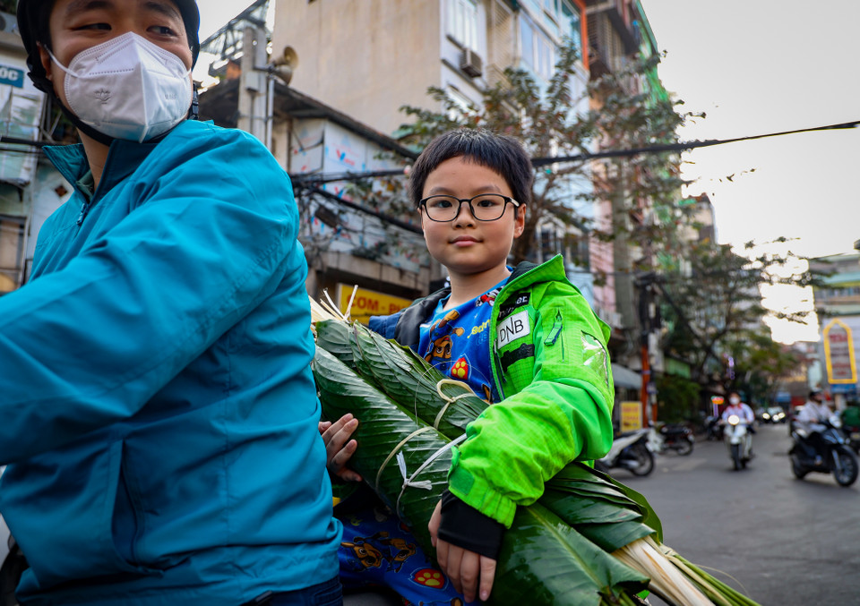 Anh Tùng (quận Đống Đa) cùng con trai mua 120 tấm lá dong để về gói bánh chưng. Anh cho biết đây là năm thứ 10 anh mua lá dong tại chợ Trần Quý Cáp. "Năm nay, tôi dẫn con đi để cho con trải nghiệm việc mua lá dong ngày Tết," anh Tùng nói. (Ảnh: Minh Hiếu/Vietnam+)