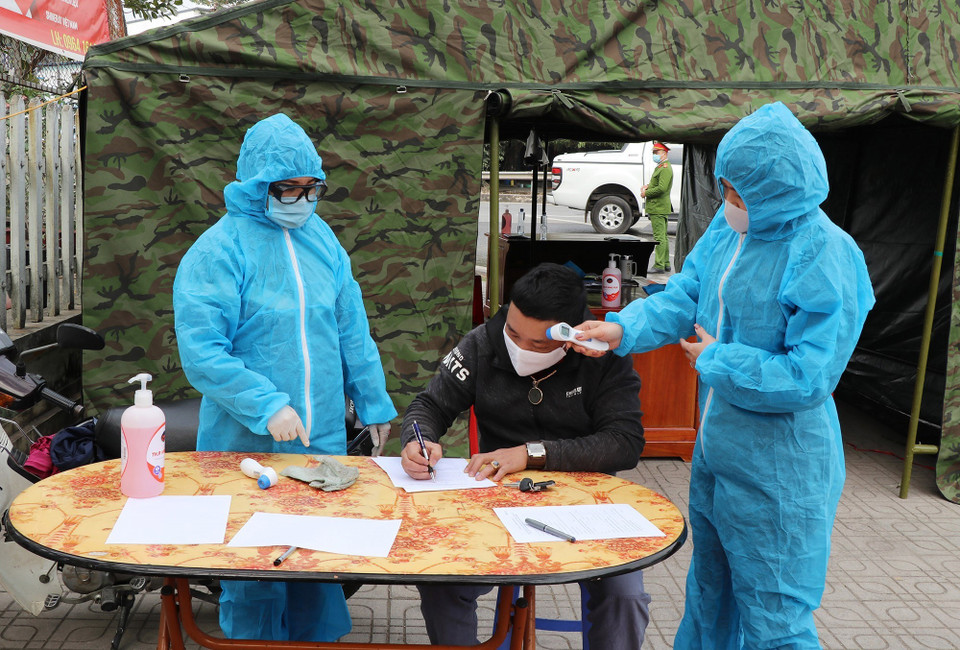 Nhân viên y tế hướng dẫn lái xe ngoại tỉnh khai báo y tế và kiểm tra thân nhiệt tại chốt kiểm tra liên ngành nút giao Thịnh Đán, thành phố Thái Nguyên. (Ảnh: Hoàng Nguyên/TTXVN)