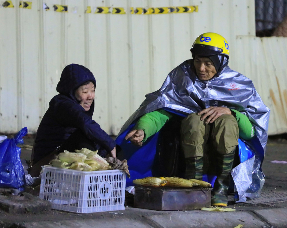 Mưu sinh trong thời tiết lạnh khoảng 10 độ C kèm gió lạnh, tối 22/1. (Ảnh: Hoàng Hiếu/TTXVN)