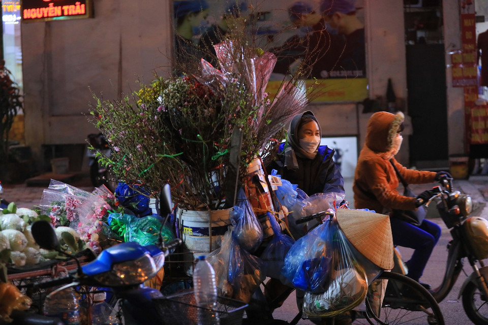 Người bán hoa mưu sinh trong thời tiết lạnh khoảng 10 độ C kèm gió lạnh, tối 22/1. (Ảnh: Hoàng Hiếu/TTXVN)