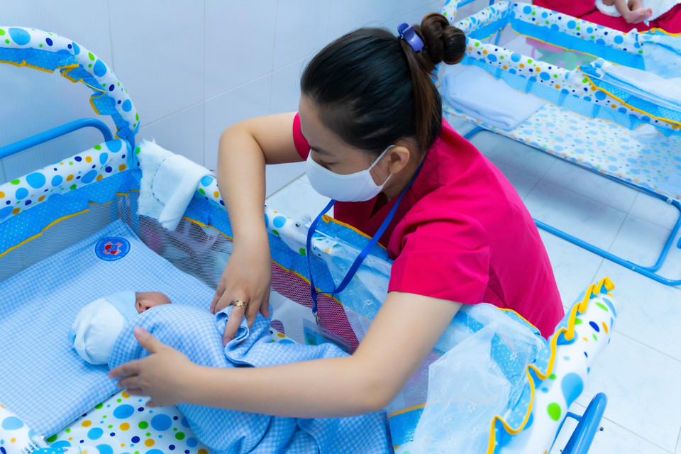 Bảo mẫu chăm sóc trẻ sơ sinh có mẹ mắc COVID-19 chờ người thân đón về. (Ảnh: TTXVN phát)