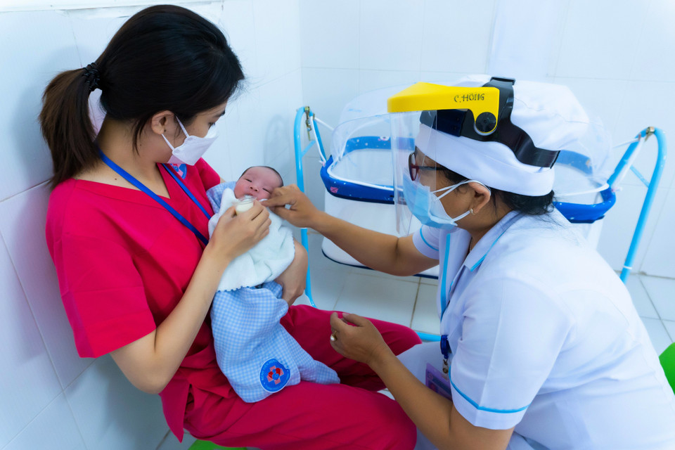 Bảo mẫu chăm sóc trẻ sơ sinh có mẹ mắc COVID-19 chờ người thân đón về. (Ảnh: TTXVN phát)