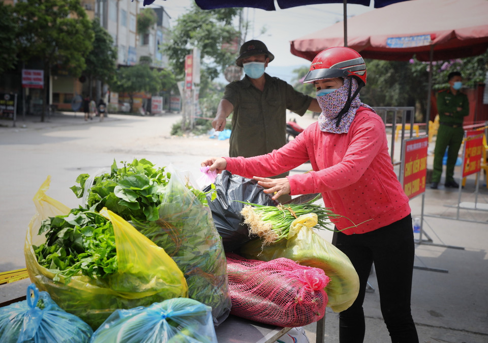 Người dân cung cấp nhu yếu phẩm vào khu cách ly theo đúng quy trình dịch tế tại chốt kiểm soát dịch tổ dân phố My Điền 1. (Ảnh: Danh Lam/TTXVN)