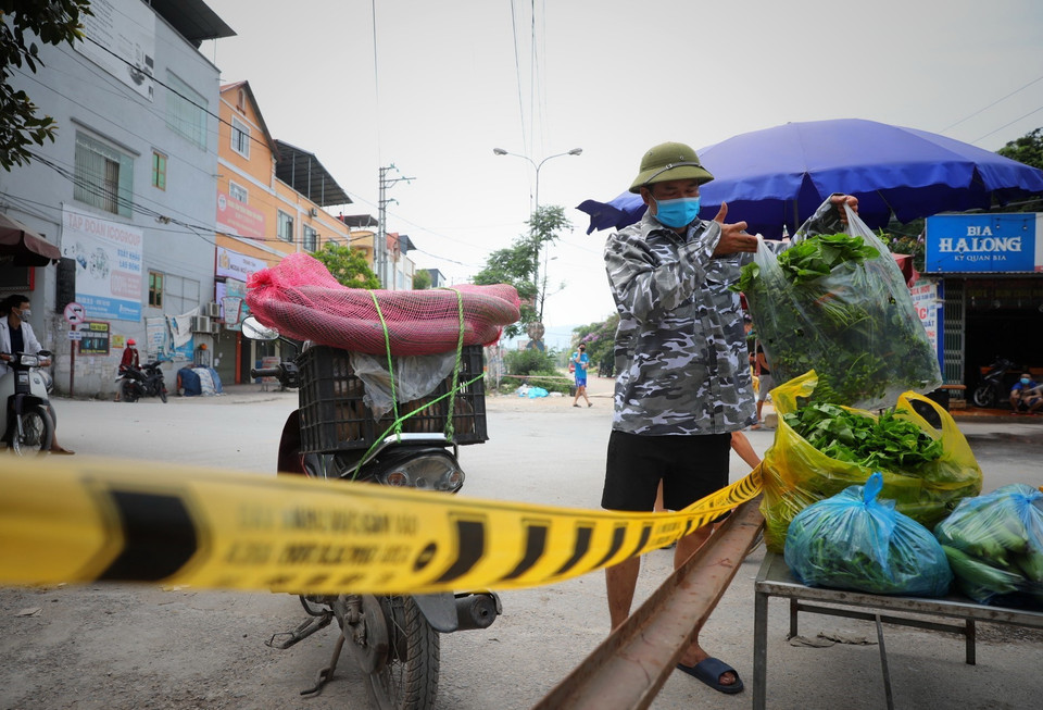Người dân cung cấp nhu yếu phẩm vào khu cách ly theo đúng quy trình dịch tế tại chốt kiểm soát dịch tổ dân phố My Điền 1. (Ảnh: Danh Lam/TTXVN)