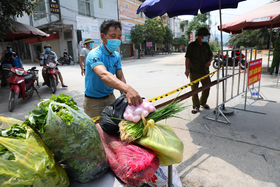 Người dân cung cấp nhu yếu phẩm vào khu cách ly theo đúng quy trình dịch tế tại chốt kiểm soát dịch tổ dân phố My Điền 1. (Ảnh: Danh Lam/TTXVN)