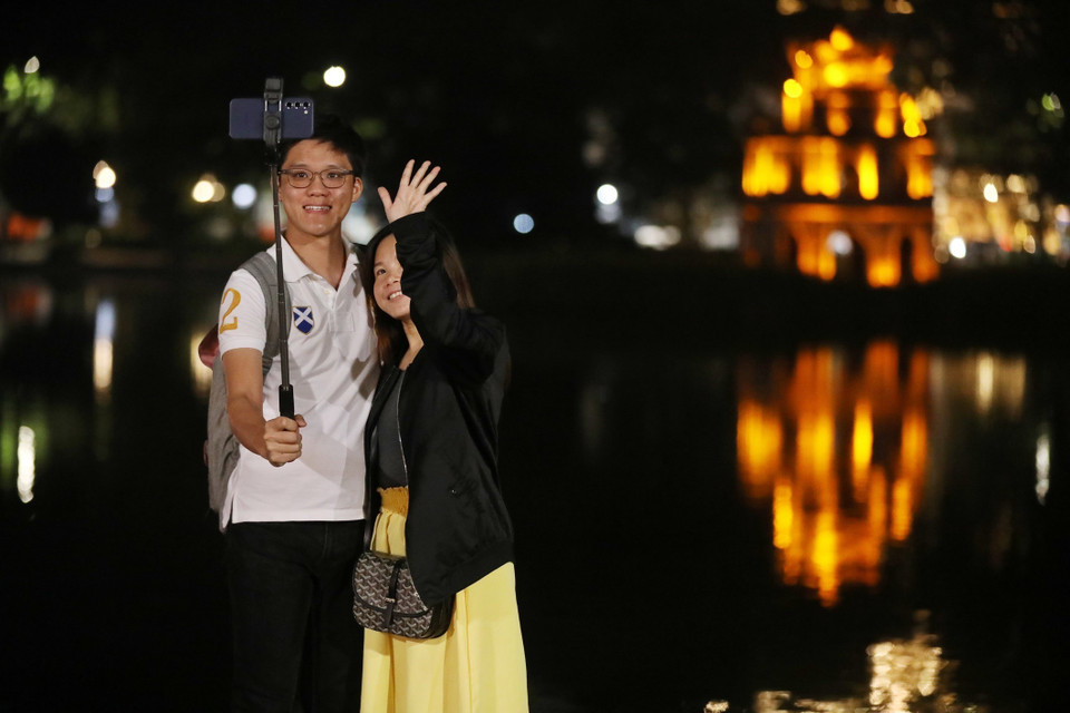 Du khách chụp ảnh check in khu vực hồ Gươm. (Ảnh: Minh Quyết/TTXVN)