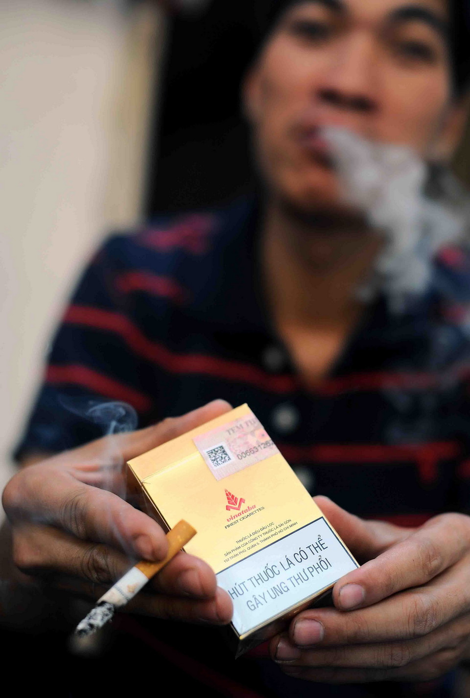Thảm nhiên hút thuốc là dù trên vỏ bao thuốc ghi rõ "Hút thuốc lá có thể gây ung thư phổi". (Ảnh: Minh Đức/TTXVN)