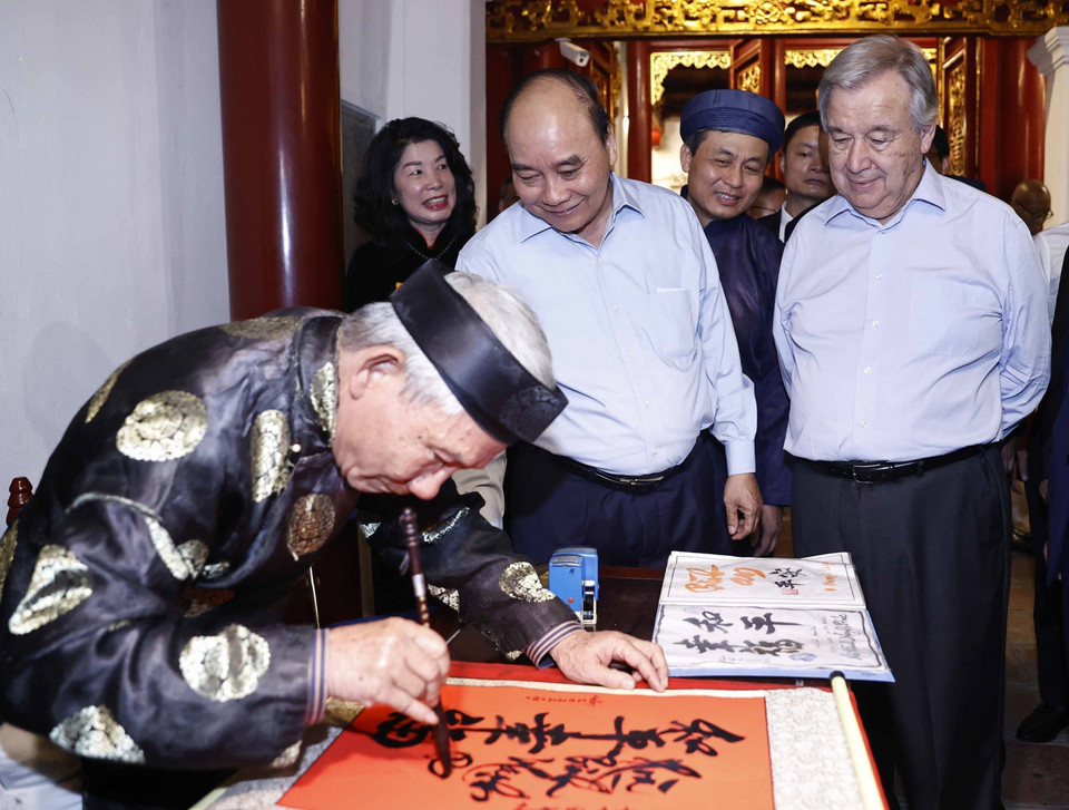 Chủ tịch nước Nguyễn Xuân Phúc và Tổng Thư ký LHQ António Guterres xem nhà thư pháp viết chữ tại đền Ngọc Sơn. (Ảnh: Thống Nhất/TTXVN)