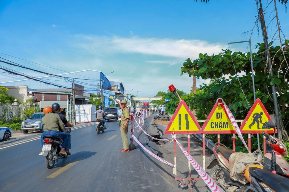 Lực lượng chức năng tổ chức phân luồng giao thông tại khu vực bị sạt lở trên Quốc lộ 80. (Ảnh: TTXVN phát)