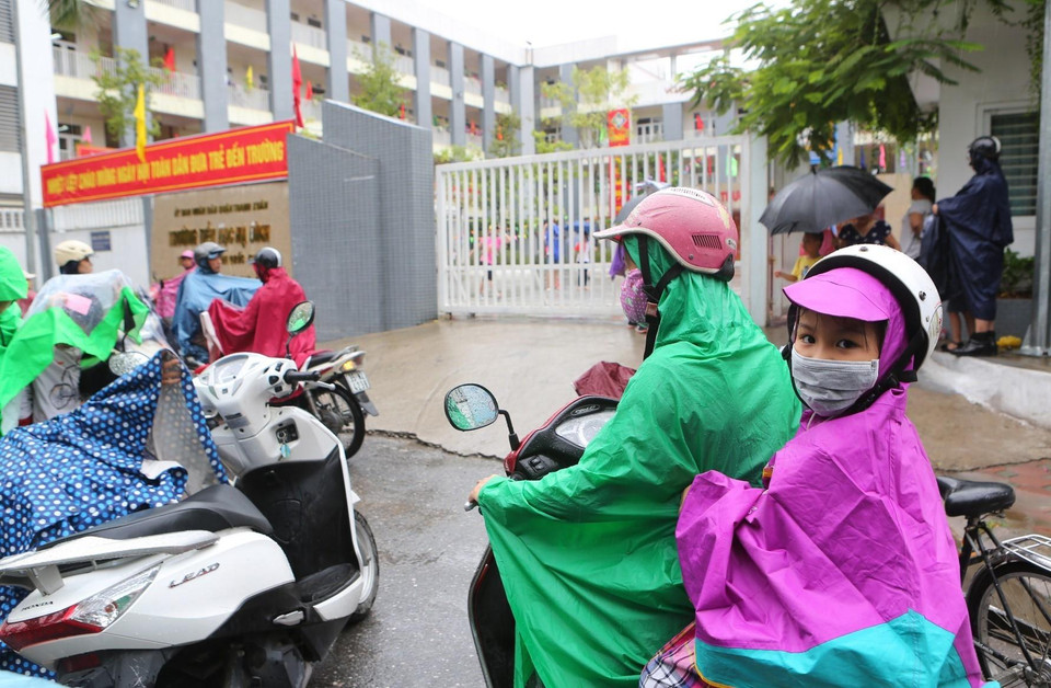 Các bậc phụ huynh đón con nhỏ luôn đeo khẩu trang tại Trường Tiểu học Hạ Đình cách hiện trường vụ cháy Nhà xưởng Công ty Phích nước Rạng Đông chưa đến 1km. (Ảnh: Thành Đạt/TTXVN)