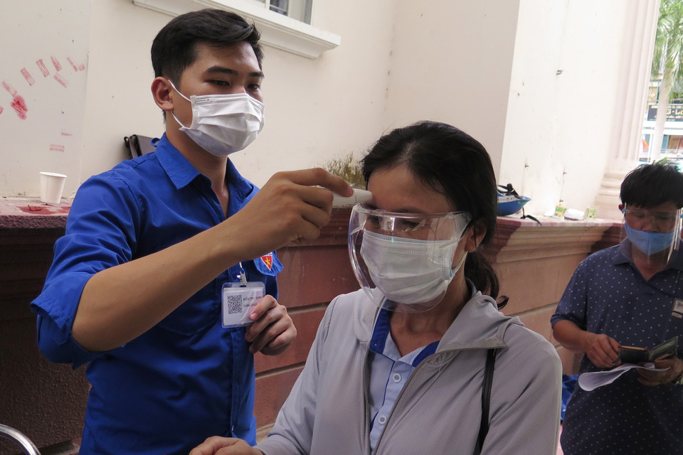 Lực lượng đoàn thanh niên hỗ trợ đo thân nhiệt cho người dân đến tiêm vaccine phòng COVID-19 tại điểm tiêm 26 Hoàng Hoa Thám, thành phố Nha Trang. (Ảnh: Phan Sáu/TTXVN)