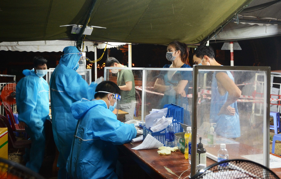 Lực lượng liên ngành tại điểm chốt Dự án tổ hợp du lịch và giải trí Cocobay hướng dẫn người dân thực hiện khai báo y tế điện tử. (Ảnh: Văn Dũng/TTXVN)