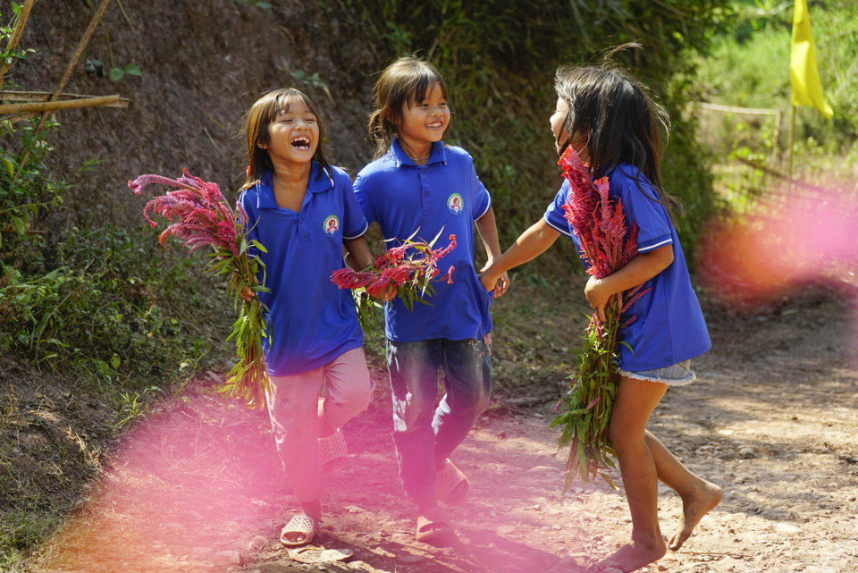 Những em bé dân tộc Cống ở Lả Chà mang hoa mào gà về trang trí nhà trong ngày Tết. (Ảnh: Xuân Tư/TTXVN)