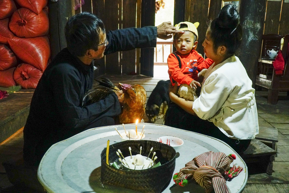 Nghi thức điểm chỉ, thầy cúng dùng tiết gà đánh dấu lên trán cho trẻ nhỏ để cầu xin thần linh phù hộ một năm mới không ốm đau, bệnh tật. (Ảnh: Xuân Tư/TTXVN)