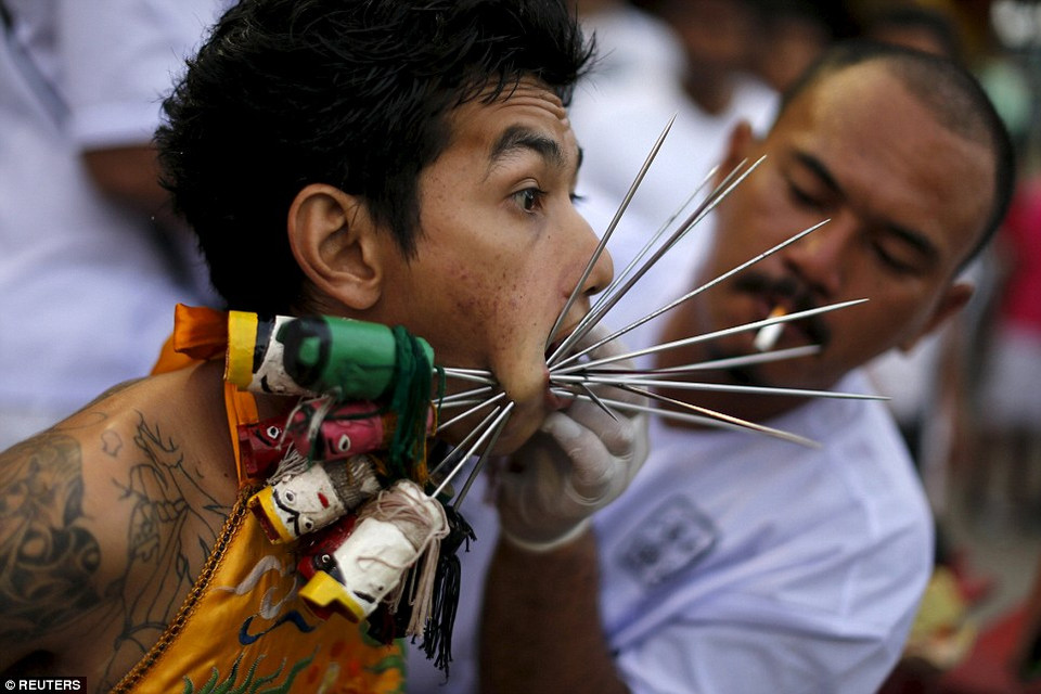 Một cậu bé dường như đang cảm thấy sốc khi một tín đồ khác đâm hàng chục que nhọn qua lớp da mỏng trên mặt cậu. (Nguồn: Reuters)