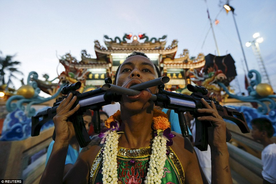 Khu vực này bao gồm rất nhiều ngôi đền, với màu sắc khớp với những bộ trang phục sặc sỡ và tỉ mỉ của những người đàn ông rước đám. Trong ảnh, một người trong số họ đã dùng nòng của hai khẩu súng để tạo ra lỗ trên má. (Nguồn: Reuters)