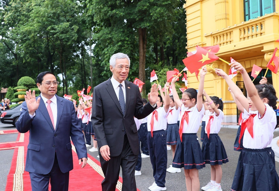 Thủ tướng Phạm Minh Chính và Thủ tướng Singapore Lý Hiển Long với thiếu nhi Thủ đô. (Ảnh: Dương Giang/TTXVN)