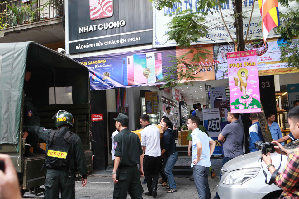 Cảnh sát kiểm tra, khám xét và đưa các kiện hàng lên xe tại cửa hàng điện thoại Nhật Cường mobile ở 33 Lý Quốc Sư, Hà Nội. (Ảnh: Doãn Tấn/TTXVN)