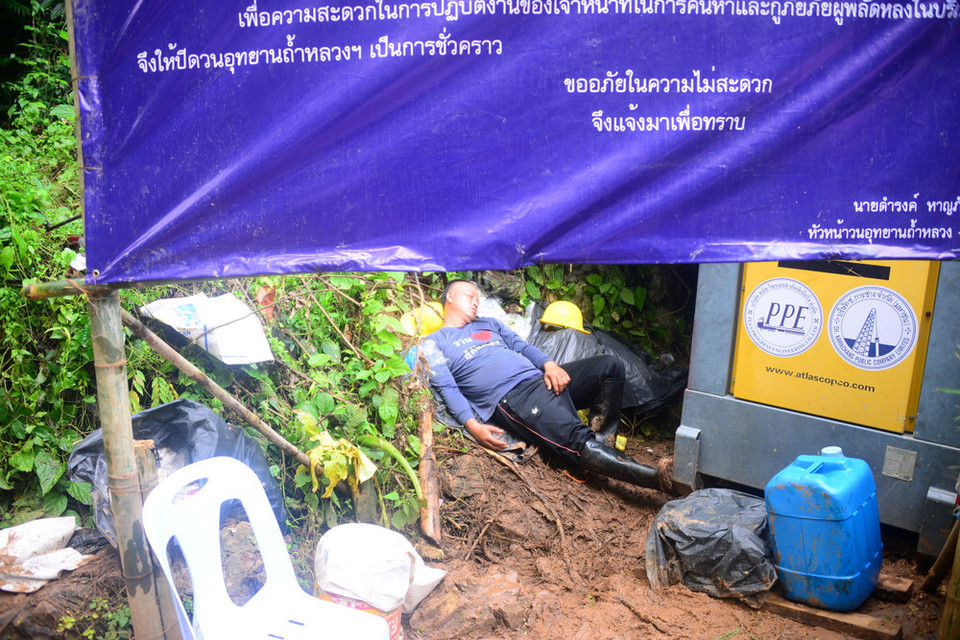 Một thành viên của đoàn cứu hộ kiệt sức ngủ ngay tại vệ đường, dự kiến công tác cứu hộ còn kéo dài vì chưa thể đưa 13 người này ra khỏi khu vực hang. (Ảnh: Sơn Nam/Vietnam+)