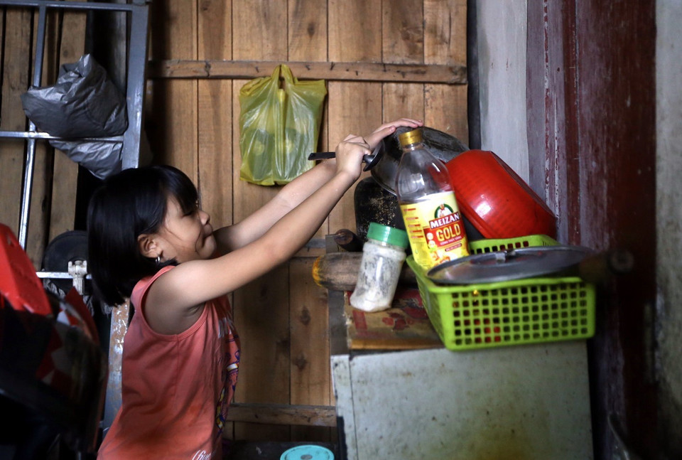 Nguyễn Đồng Trà Mỹ (8 tuổi) đã phải tự nấu cơm, trông em trong khi bố mẹ đi làm. (Ảnh: Hoàng Hiếu/TTXVN)