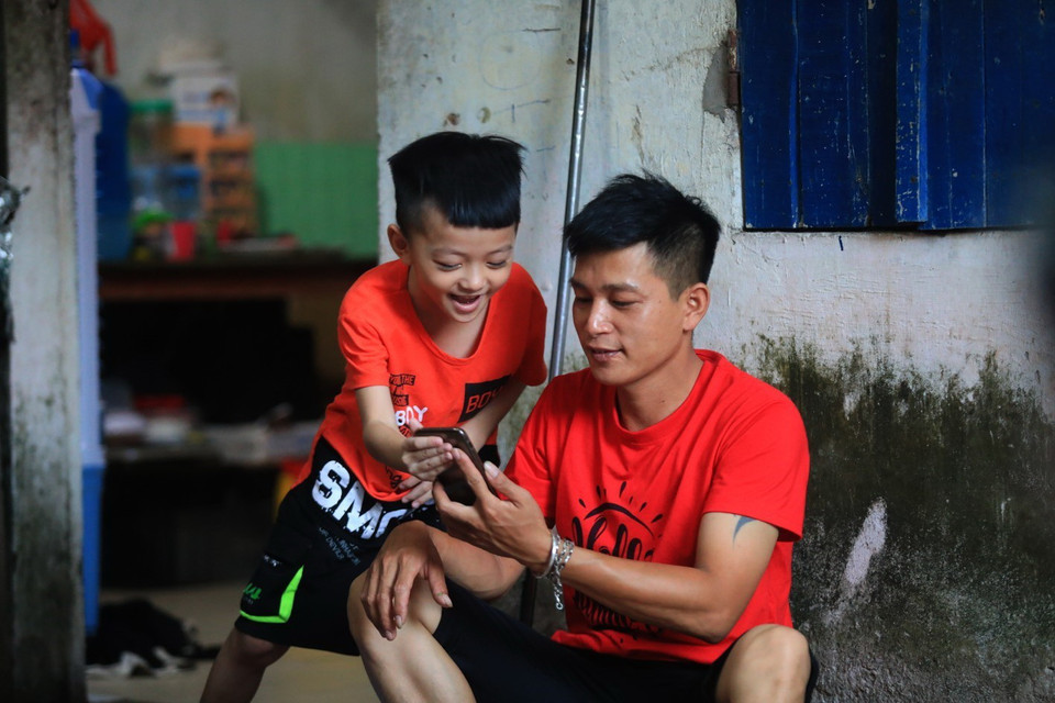 Không thể về quê trong những ngày giãn cách, anh Nguyễn Văn Toàn (Công ty Cổ phần Kỹ thuật bao bì Cửu Long, khu công nghiệp Quang Minh) cùng con trai thường xuyên gọi điện hỏi thăm ông bà và gia đình. (Ảnh: Phan Tuấn Anh/TTXVN)