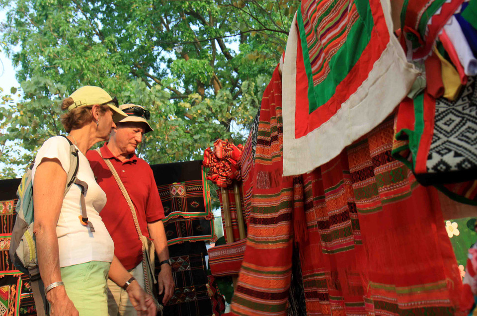 Du khách quốc tế tìm hiểu về sản phẩm thủ công truyền thống của dân tộc Thái. (Ảnh: Thanh Tùng/TTXVN)