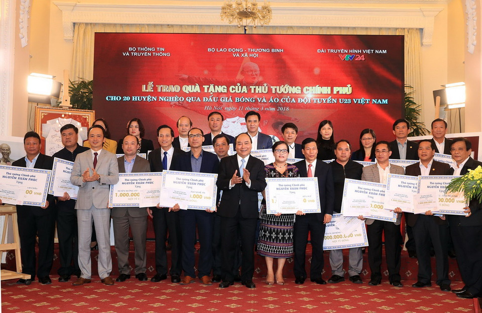 Thủ tướng Nguyễn Xuân Phúc trao tặng tiền số tiền cho 20 huyện nghèo qua đấu giá trái bóng và áo Đội tuyển U23 Việt Nam. (Ảnh: Thống Nhất/TTXVN)