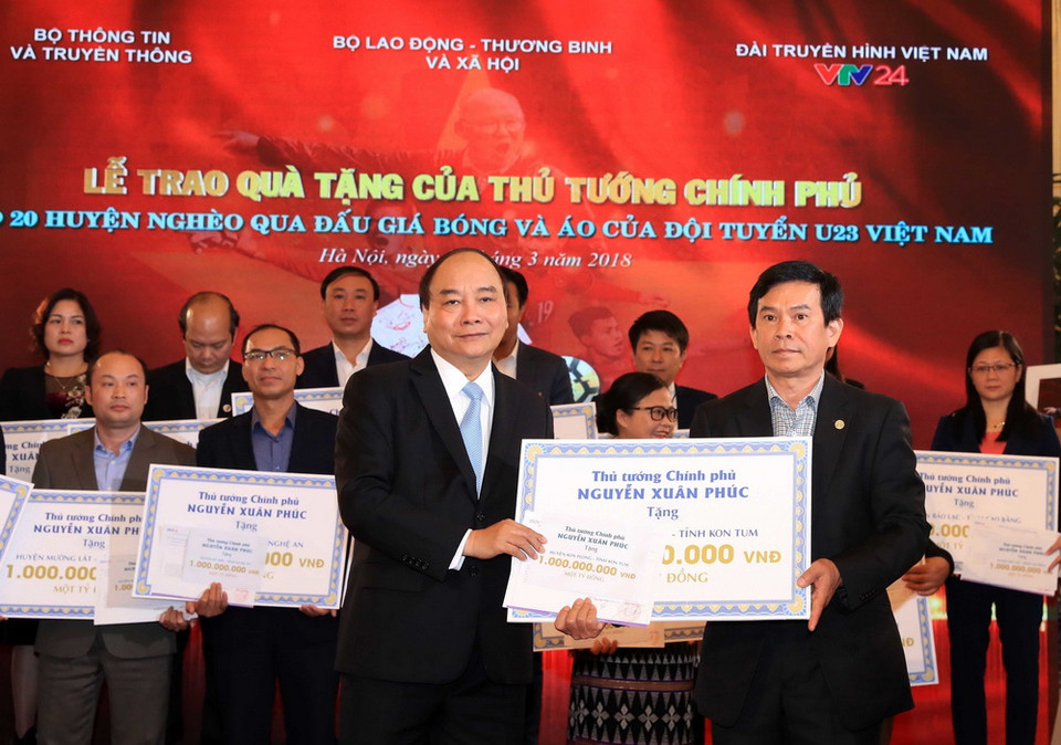 Thủ tướng Nguyễn Xuân Phúc trao tặng tiền số tiền cho 20 huyện nghèo qua đấu giá trái bóng và áo Đội tuyển U23 Việt Nam. (Ảnh: Thống Nhất/TTXVN)