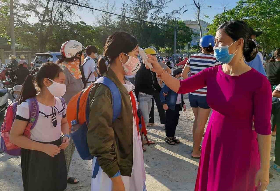 Giáo viên trường Tiểu học Lạc Long Quân (thành phố Tuy Hòa, Phú Yên) đo thân nhiệt cho học sinh trước khi vờ lớp. (Ảnh: Xuân Triệu/TTXVN)