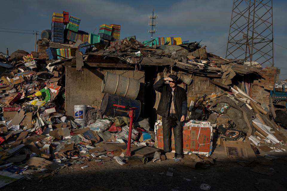 Người đàn ông đang đứng đợi cân hàng hóa thu thập được trước khi đem bán. (Ảnh: Kevin Frayer/Getty Images)