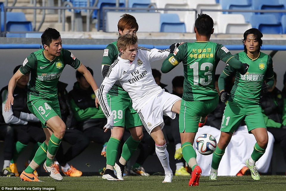 Odegaard vượt qua vòng vây của các cầu thủ Beijing Guoan.
