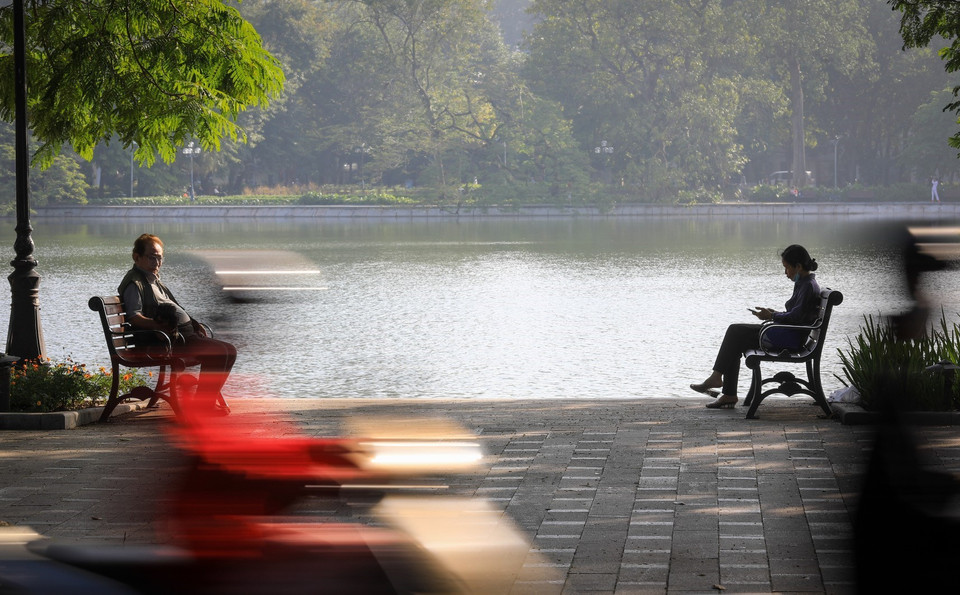 Người dân Thủ đô thư thái ngồi cảm nhận ánh nắng ban mai và tiết thu se lạnh ở hồ Hoàn Kiếm. (Ảnh: Thành Đạt/TTXVN)