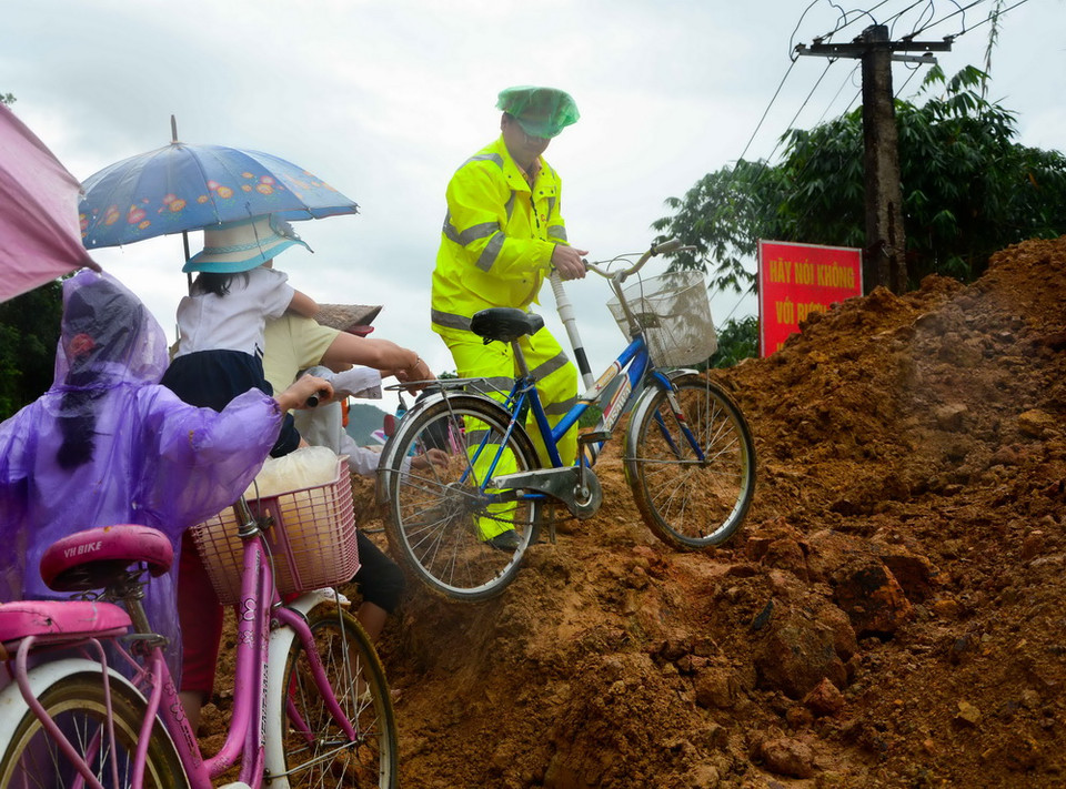 Lực lượng Cảnh sát giao thông giúp các em học sinh di chuyển qua điểm sạt lở để tới trường. (Ảnh: Xuân Tư/TTXVN)