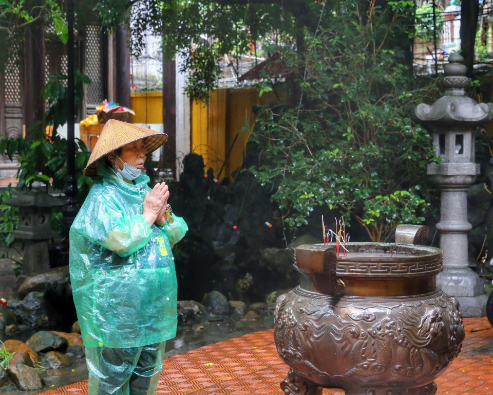Người dân thành tâm cầu khấn tại chùa Phúc Khánh cho dù trời mưa to. (Ảnh: Tuấn Đức/TTXVN)