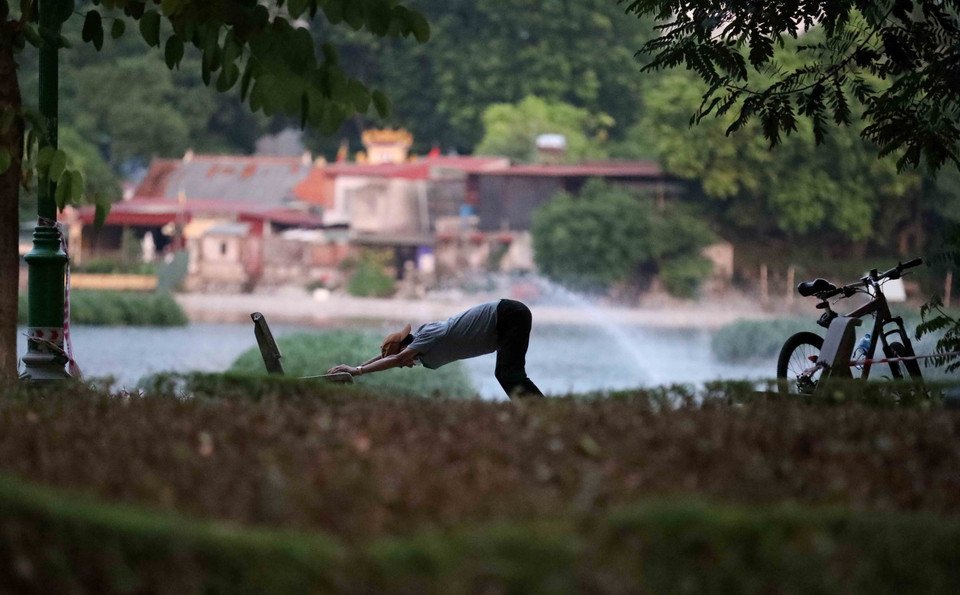 Vượt qua rào chặn để vào tập thể dục tại hồ Thiền Quang lúc 5h sáng 26/7. (Ảnh: Nhật Anh/TTXVN)