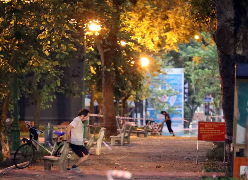 Vượt qua rào chặn để vào tập thể dục tại hồ Thiền Quang lúc 5h sáng 26/7. (Ảnh: Nhật Anh/TTXVN)